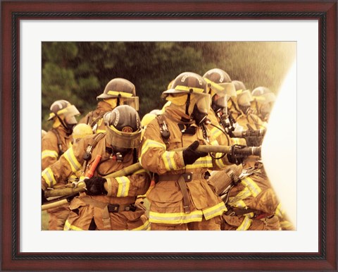 Framed Group of firefighters spraying water with a fire hose Print