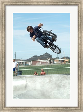 Framed Low angle view of a teenage boy performing a stunt on a bicycle over ramp Print