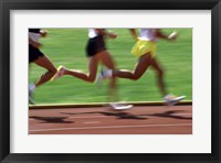 Framed Low section view of male athletes running on a running track