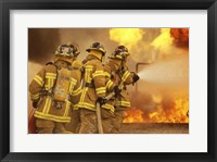 Framed Rear view of a group of firefighters extinguishing a fire and flames