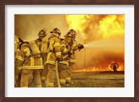 Framed Rear view of a group of firefighters extinguishing a fire