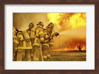 Framed Rear view of a group of firefighters extinguishing a fire