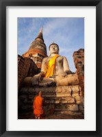 Framed Monk praying in front of a statue of Buddha