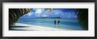 Framed Rear view of two native teenage girls in lagoon, framed by palm tree, Aitutaki, Cook Islands.