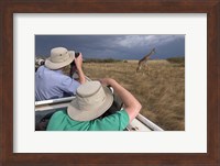 Framed Rear view of two safari photographers filming a giraffe